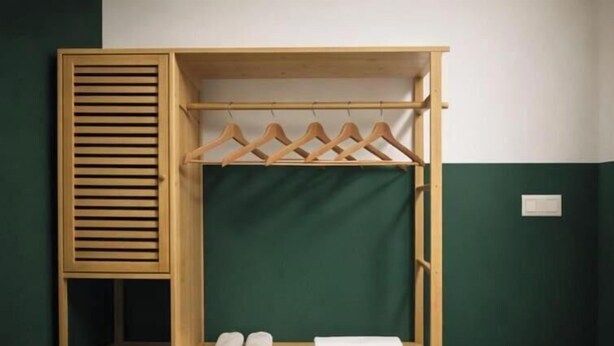 A wooden wardrobe with a hanging space, a shelf with shoes, and a folded towel.
