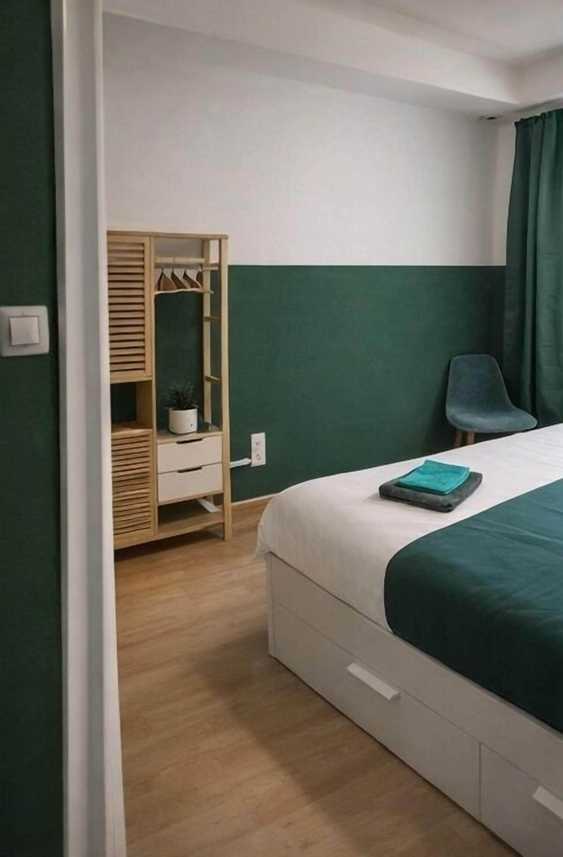 Un dormitorio con cama, armario de madera, escritorio y silla.