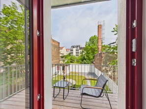 A balcony with two chairs, a view of a residential area, and a brick chimney. - Group apartment with balcony, up to 5 persons - GÖ05 (Görlitz)