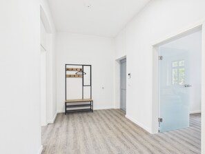 A hallway with a coat rack, a door, and a light switch on the wall. - Group apartment with balcony, up to 5 persons - GÖ05 (Görlitz)