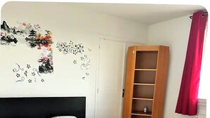 Makuuhuoneessa on suuri sänky, puinen vaatekaappi ja punainen verho.