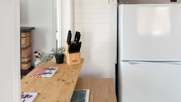 A kitchen with a wooden table, a knife block, a refrigerator, and a hanging light fixture. - Retro Retreat - Riverfront Access - St. Clair River (st clair)