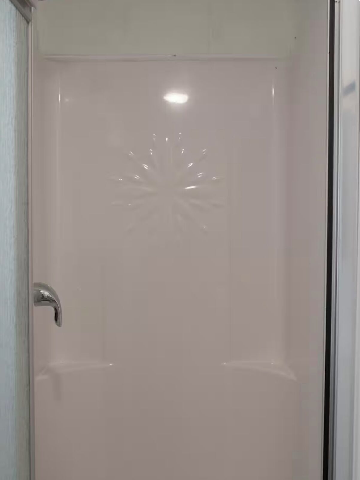 Een witte deur met een metalen handvat en een decoratief zonvlechtpatroon.