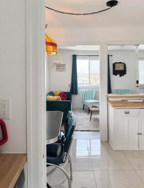 Una cocina moderna con armarios blancos, encimera de madera y comedor con mesa y sillas.