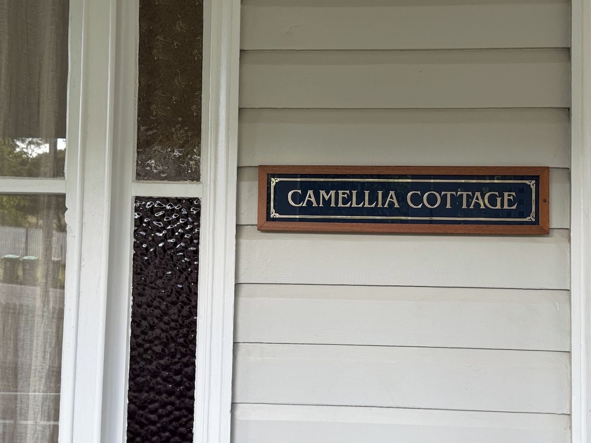 Et hus med et skilt, der står 'Camellia Cottage'.