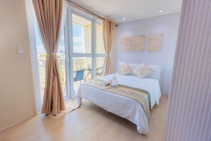 Una camera d'albergo con un letto, tende, vista attraverso una porta di vetro e un balcone con una sedia.