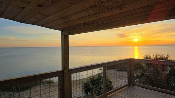 Een houten terras met uitzicht op de oceaan bij zonsondergang.