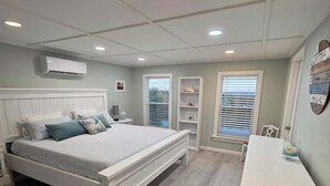 Een slaapkamer met een bed, nachtkastjes, een bureau en een kledingkast.
