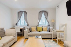 A living room with two sofas, a coffee table, a lamp, and a desk with a fan. - Brilliantly Located 1BD Flat by Piccadilly Circus (Greater London)