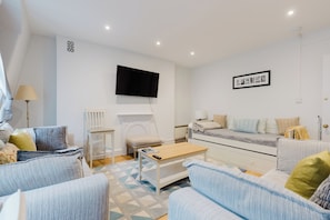 Een moderne woonkamer met een zithoek, een salontafel, een flatscreen televisie aan de muur en een kamerbreed tapijt.