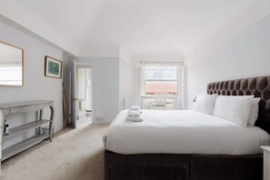 Ein Schlafzimmer mit Bett, Schreibtisch, Stuhl und Fenster.