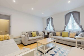 Ein modernes Wohnzimmer mit einer Sofagarnitur, einem Couchtisch und einem Schreibtisch mit Stuhl.
