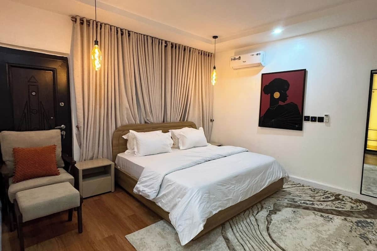 Une chambre à coucher comprenant un lit, une chaise, un tapis et un climatiseur fixé au mur.