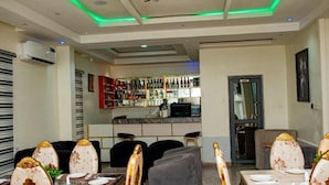 A dining area with a bar in the background, featuring a modern design with a marble countertop and a variety of bottles.