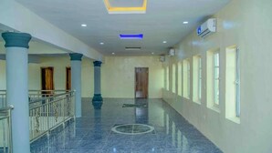A corridor with marble flooring, columns, and a ceiling with recessed lighting.