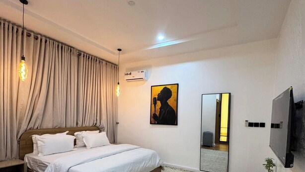 A bedroom with a bed, a large mirror, a TV, and an air conditioning unit.