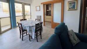 Un comedor con mesa y sillas, una cocina al fondo y un sofá azul con un cojín.