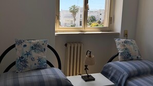 Un dormitorio con dos camas, una ventana, un radiador y una lámpara en una mesita de noche.