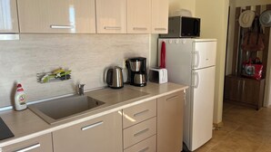 A kitchen with a sink, stainless steel kettle, toaster, and a white refrigerator. - Two-room apartment 350 m from the beach, good infrastructure, quiet location (Sweti Wlas)