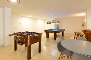 A room with a foosball table, a pool table, and a dining table with chairs. - Mirador House (Vila Garcia)