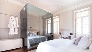 A hotel room with a large bed, a desk, a mirror, and a wardrobe.