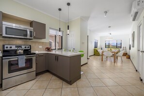 Eine moderne Küche mit eingebauter Mikrowelle, Herd und Backofen, einem Essbereich mit Tisch und Stühlen sowie einer Aussicht ins Freie durch ein Fenster.
