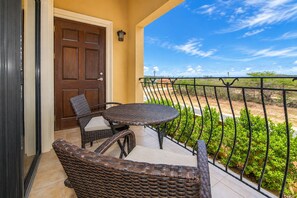 Un balcon avec des meubles en osier, une porte et une vue sur un paysage désertique.