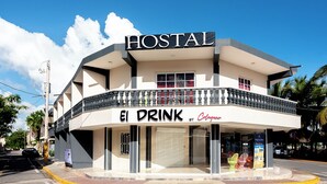 Un immeuble de deux étages, avec une enseigne indiquant « HOSTAL » et « El Drink by Colgate » au rez-de-chaussée.
