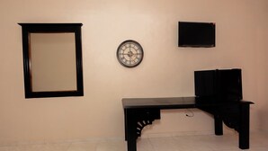 Une pièce avec un bureau noir, une horloge murale et un miroir encadré.