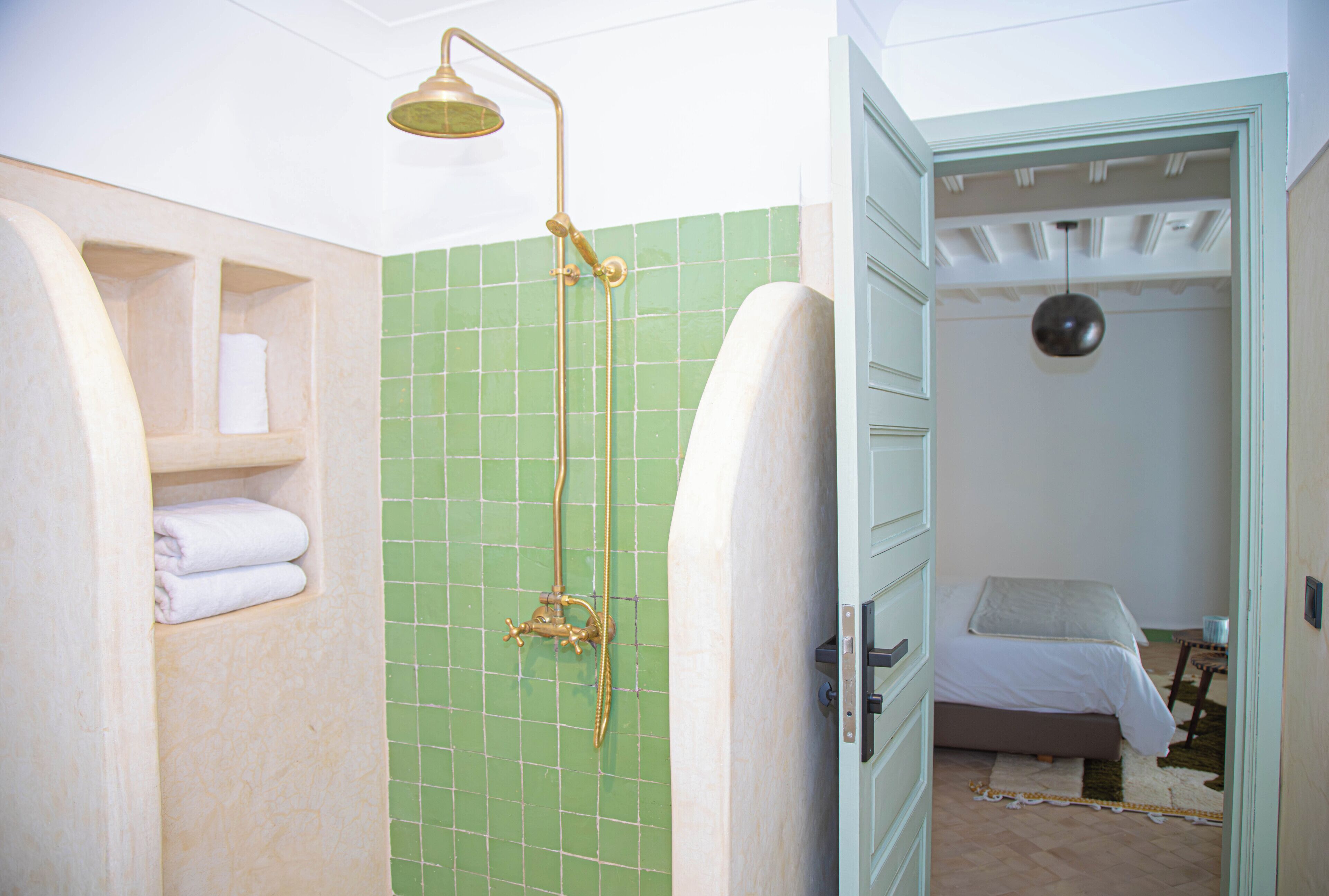 Een badkamer met een douche en toilet, plus een bed in de aangrenzende kamer.
