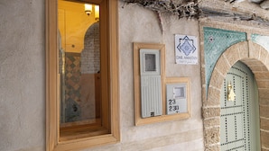 A building entrance with a wooden door, a window, and a wall-mounted sign with a number.