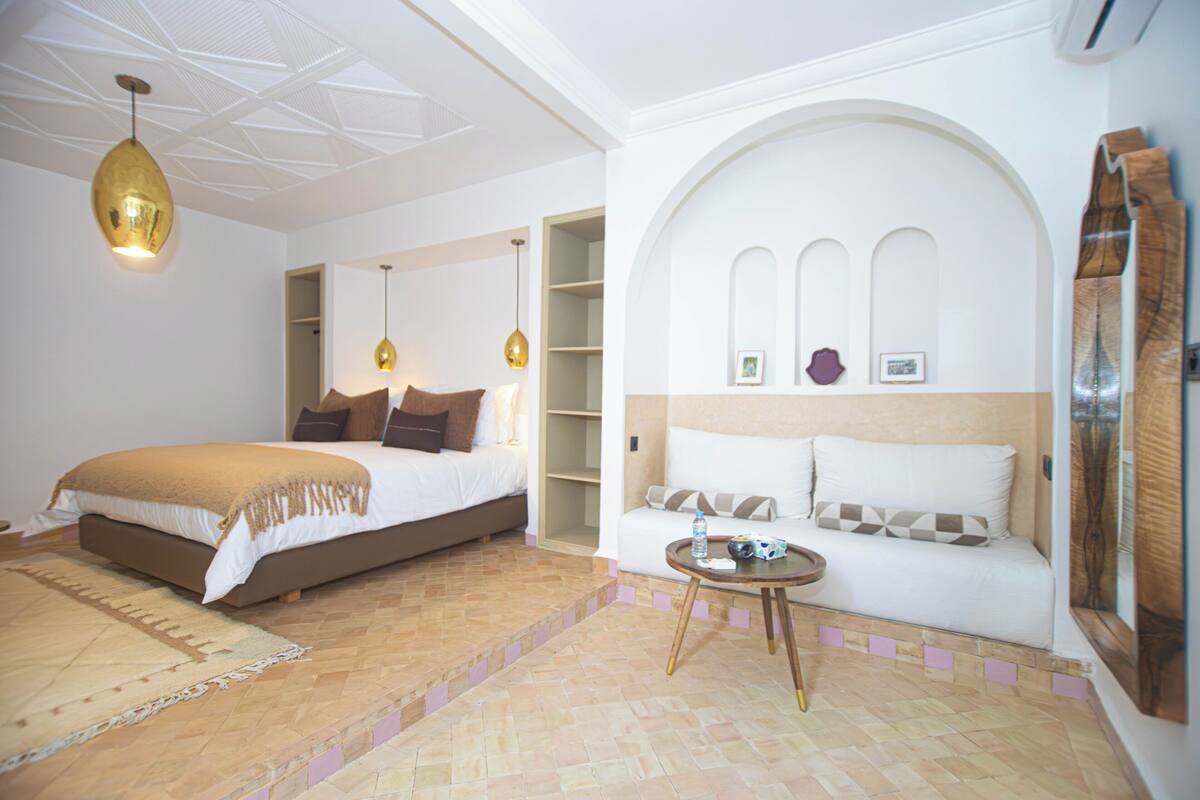 Ein Hotelzimmer mit einem Bett, einer Couch, einem kleinen Tisch und einer dekorativen Decke.
