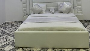 A modern bedroom with a large bed, a padded headboard, and a marble-patterned floor. - Spanish Hotel Ikeja (Lagos)