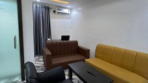 A modern hotel room with a marble floor, a brown sofa, a yellow sofa, a black armchair, and a black coffee table. - Spanish Hotel Ikeja (Lagos)