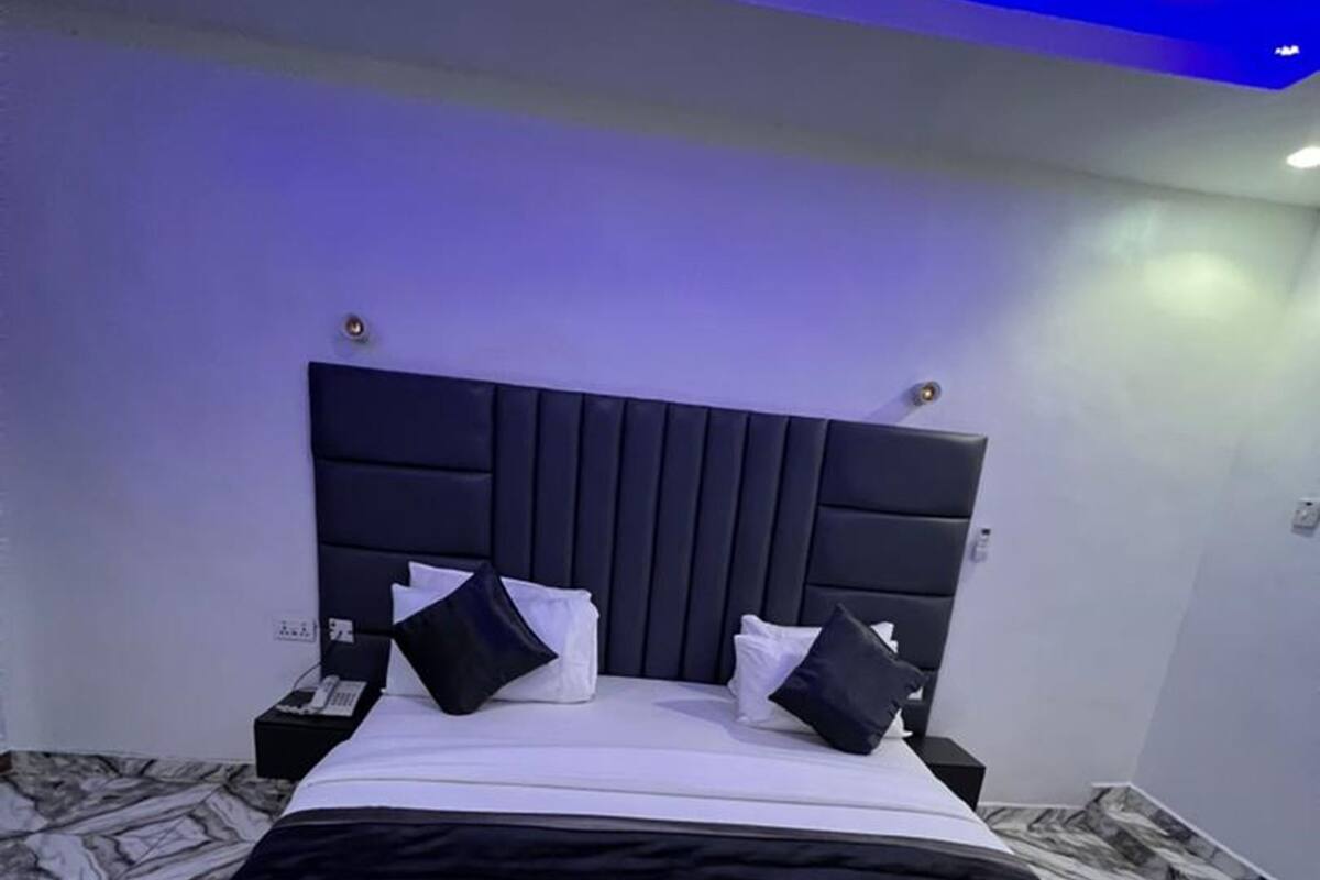 Une chambre moderne avec un grand lit, une tête de lit et un sol à motifs de marbre.