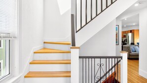 A staircase with wooden steps and a black railing, leading to a lower level. - The Milton Manor 5BR 2BA - Sleeps 10 - Unit 2 (Milton)