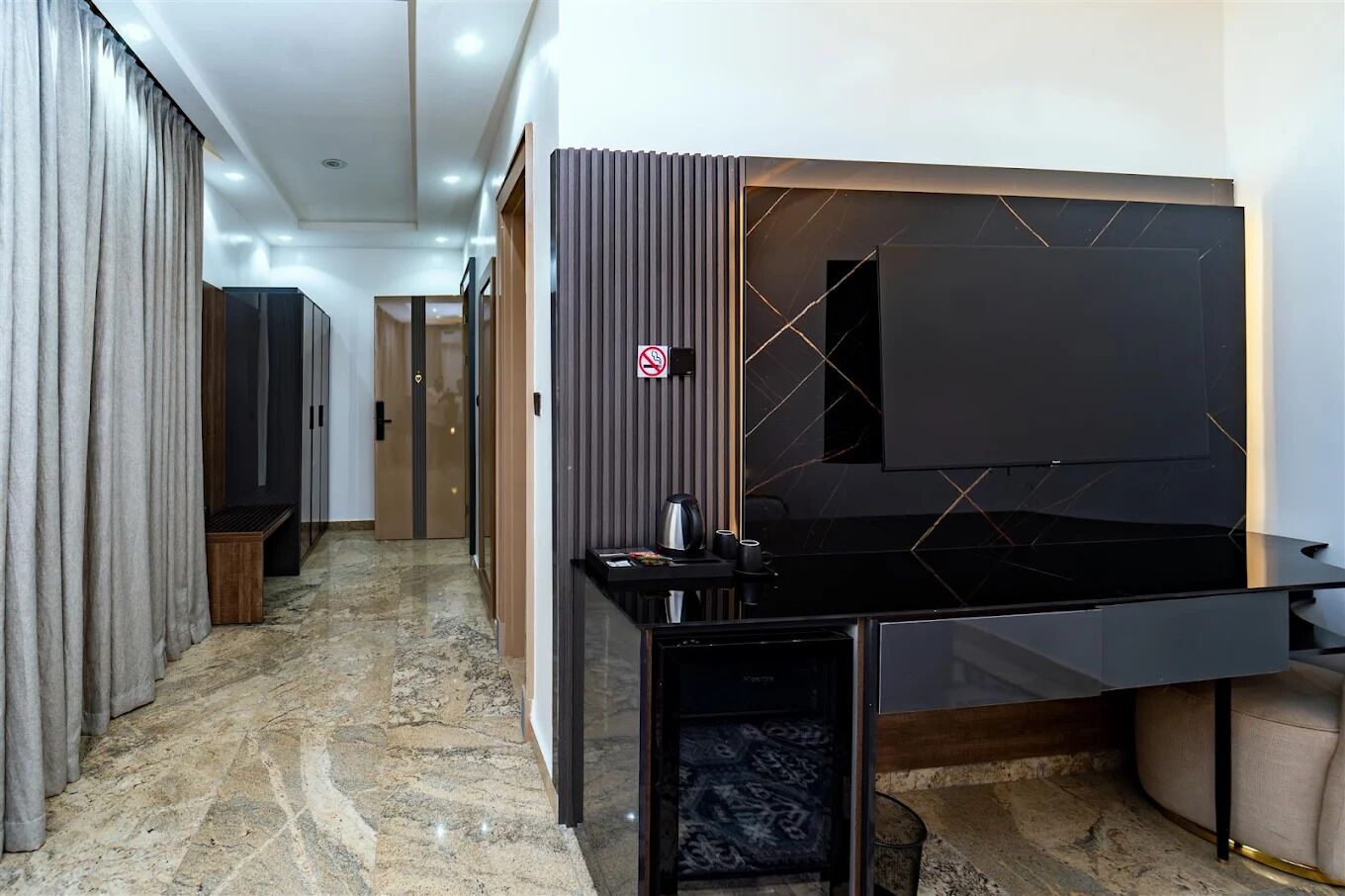 A modern hotel room with a large flat-screen TV, a small coffee table, and a seating area with a cushioned bench.