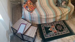 Ein gestreiftes Sofa mit dekorativen Kissen, ein kleiner Holztisch mit einem gemusterten Tablett und ein dekorativer Teppich.