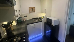 A compact kitchen with a sink, stove, and microwave. - Modern 2 BDR APT Havelock Road UB2 (Greater London)