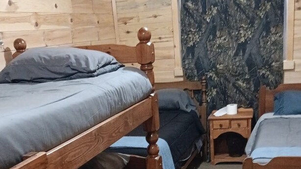 Una camera con letti a castello, uno sgabello, un comodino e un quadro appeso al muro.