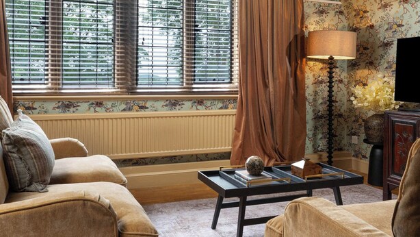 Una sala de estar con dos sofás, una mesita de centro, una lámpara y una ventana con persianas.