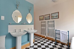 A bathroom with two sinks, a toilet, a towel rack, and a checkered floor. - The Lady Rothschild Dairy (Peterborough)