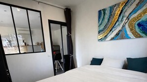 Et hotelværelse med en stor seng, et spejl, et maleri og udsigt ud