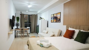 Een hotelkamer met een bed, een bureau, een stoel, een ventilator en een televisietoestel.