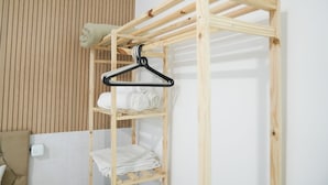 Een houten stapelbed met een hangende rek en keurig opgevouwen handdoeken.