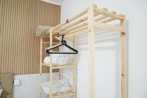 Ein hölzernes Etagenbett mit Kleiderstange und ordentlich gefalteten Handtüchern.