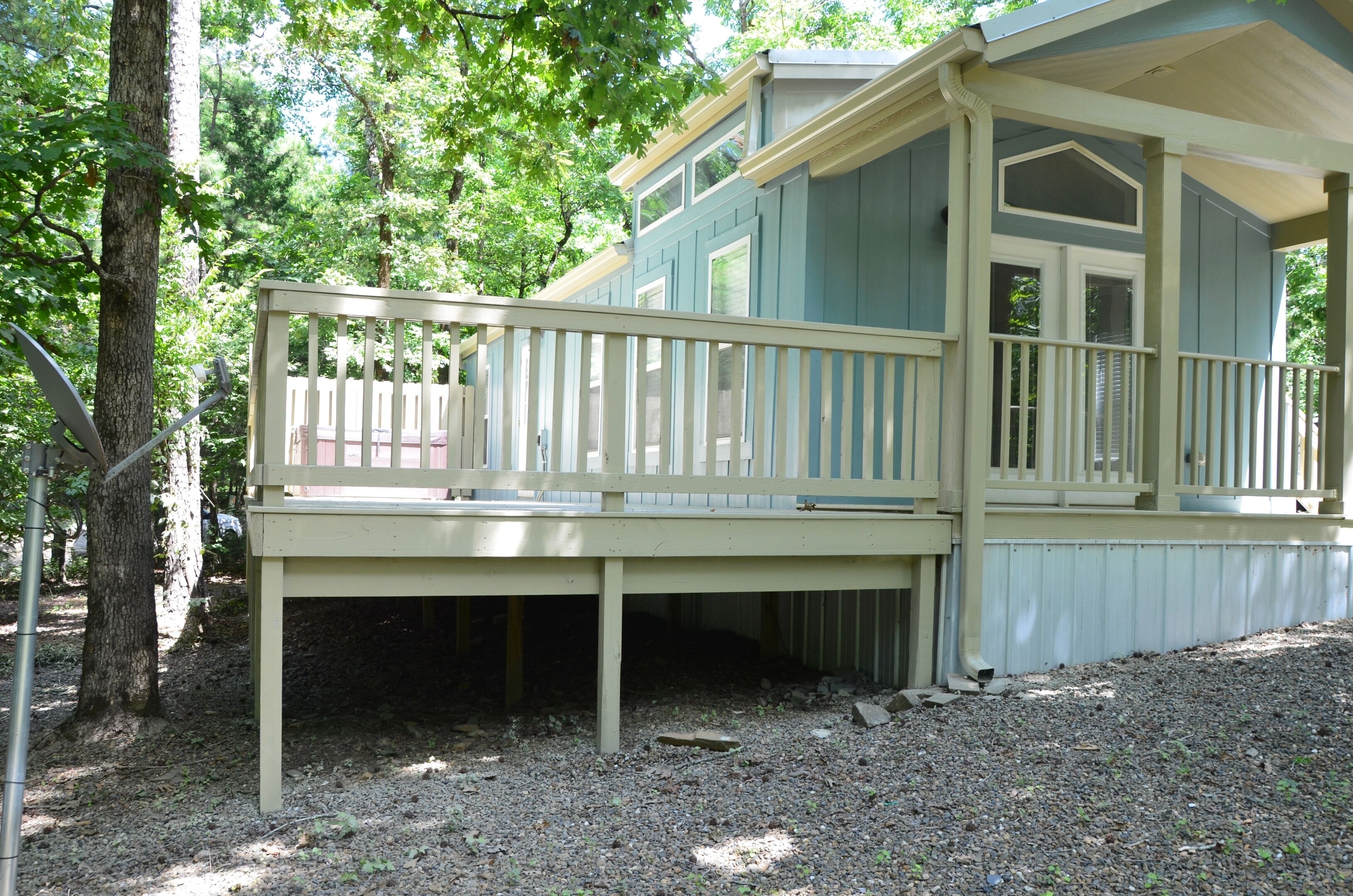 A wooden deck with a railing, a covered porch, and a building with a gabled roof.