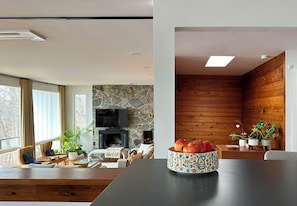 Una sala de estar moderna con chimenea de piedra, paneles de madera y un comedor con mesa y sillas.