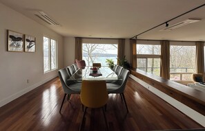 Un comedor moderno con una mesa de vidrio, sillas de cuero y vistas a un lago a través de amplios ventanales.