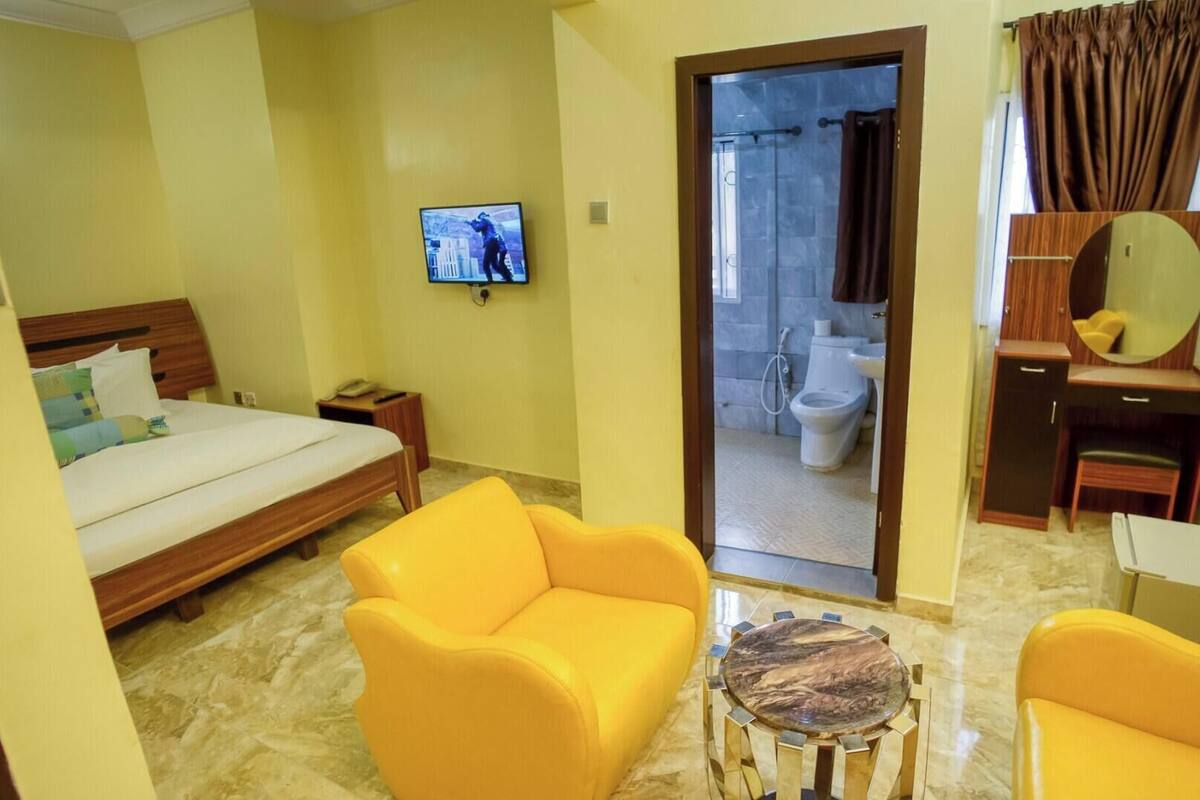 A hotel room with a bed, a television, a bathroom visible through an open door, and a small round table with a marble top.
